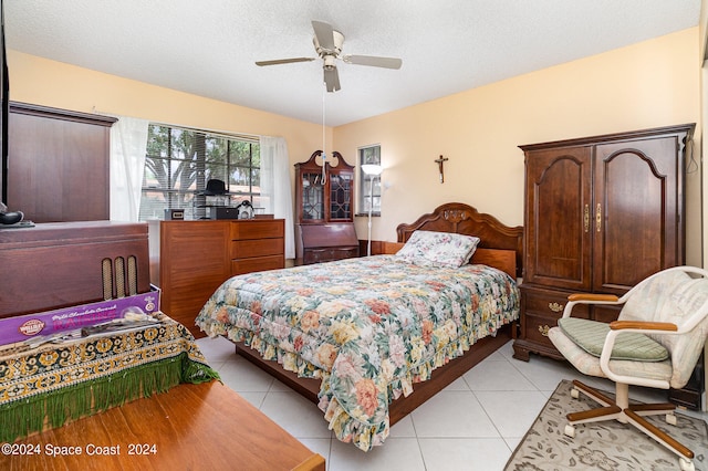 bedroom featuring ceiling fan, light tile patterned floors, and a textured ceiling