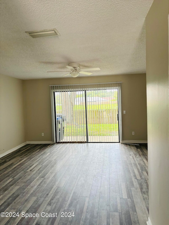 empty room with a wealth of natural light, wood-type flooring, and ceiling fan