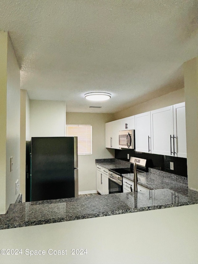 kitchen with appliances with stainless steel finishes, white cabinetry, and kitchen peninsula