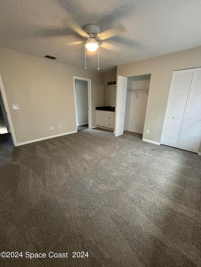 unfurnished bedroom featuring a textured ceiling, two closets, ceiling fan, and carpet