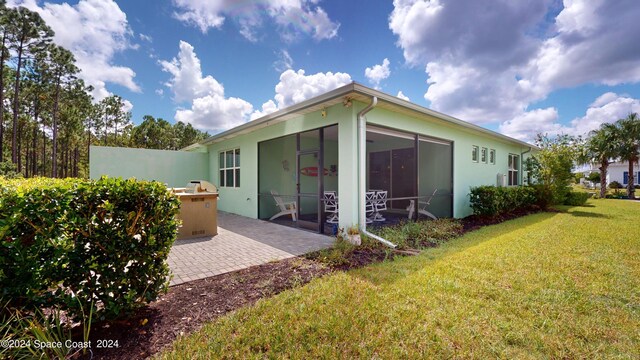 rear view of property featuring area for grilling, a lawn, and a patio