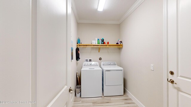 laundry area with washer and dryer, crown molding, and light wood-type flooring