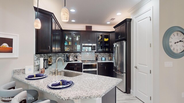 kitchen with a kitchen breakfast bar, kitchen peninsula, sink, hanging light fixtures, and appliances with stainless steel finishes