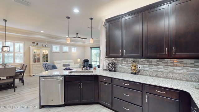 kitchen featuring decorative light fixtures, light stone counters, kitchen peninsula, and stainless steel dishwasher