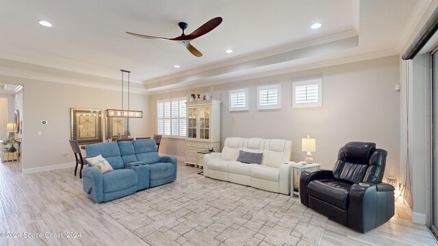 living room featuring a tray ceiling, crown molding, ceiling fan, and light hardwood / wood-style floors