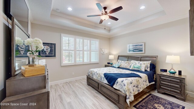 bedroom featuring a raised ceiling, ceiling fan, and light hardwood / wood-style floors