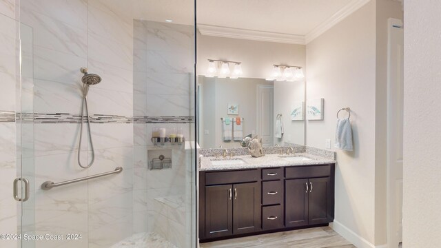 bathroom featuring vanity, a shower with shower door, and ornamental molding