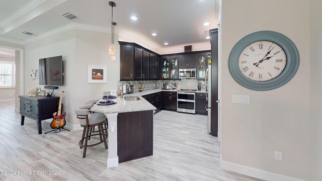 kitchen with hanging light fixtures, light stone countertops, sink, kitchen peninsula, and a kitchen bar