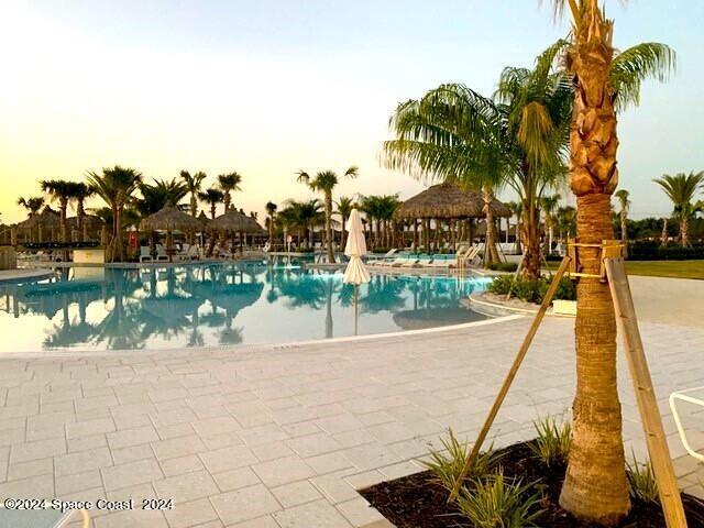 pool at dusk with a patio area and a gazebo