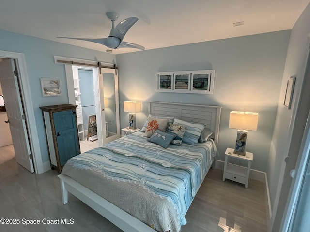 bedroom featuring wood-type flooring, a barn door, and ceiling fan