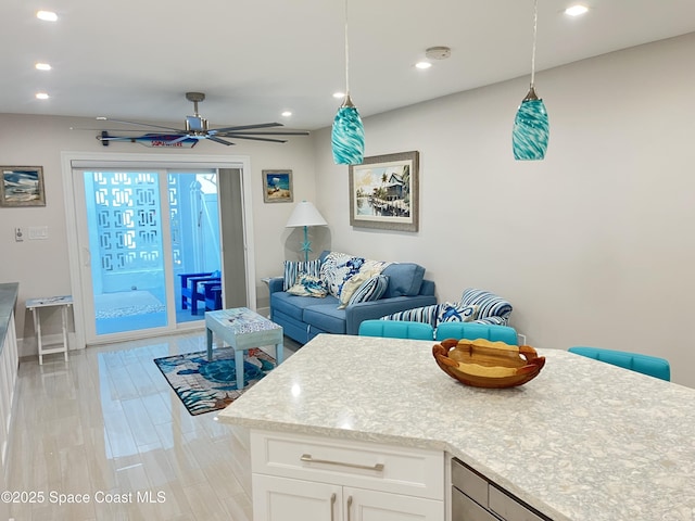 kitchen featuring white cabinetry, hanging light fixtures, light stone countertops, and ceiling fan