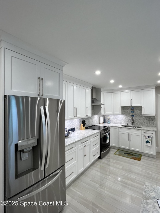 kitchen featuring wall chimney exhaust hood, sink, appliances with stainless steel finishes, white cabinets, and backsplash