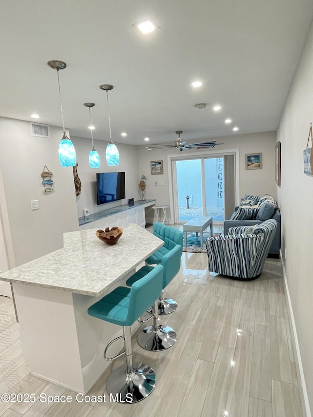 interior space with ceiling fan, decorative light fixtures, and a kitchen breakfast bar