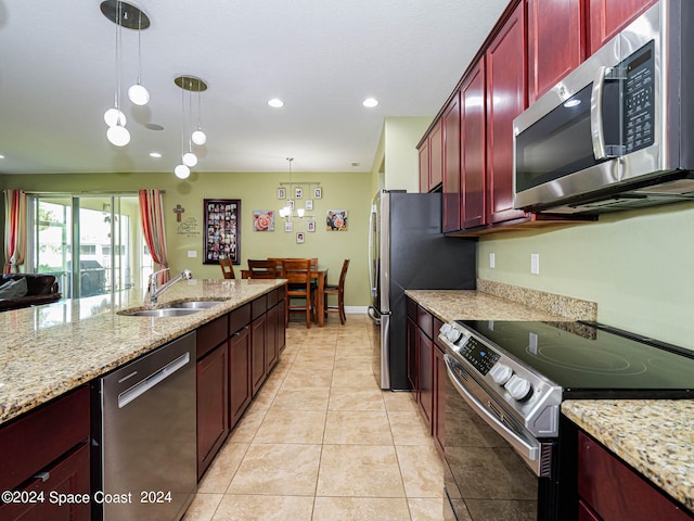 kitchen featuring appliances with stainless steel finishes, light stone counters, pendant lighting, and sink