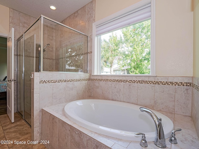 bathroom with tile patterned flooring, shower with separate bathtub, and a textured ceiling