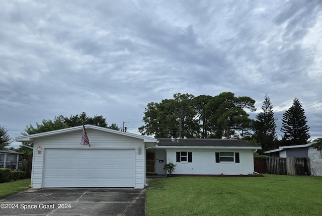 ranch-style house featuring an attached garage, driveway, fence, and a front yard