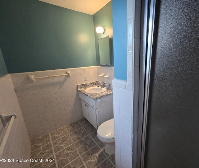 bathroom featuring tile walls, tile patterned flooring, toilet, and vanity