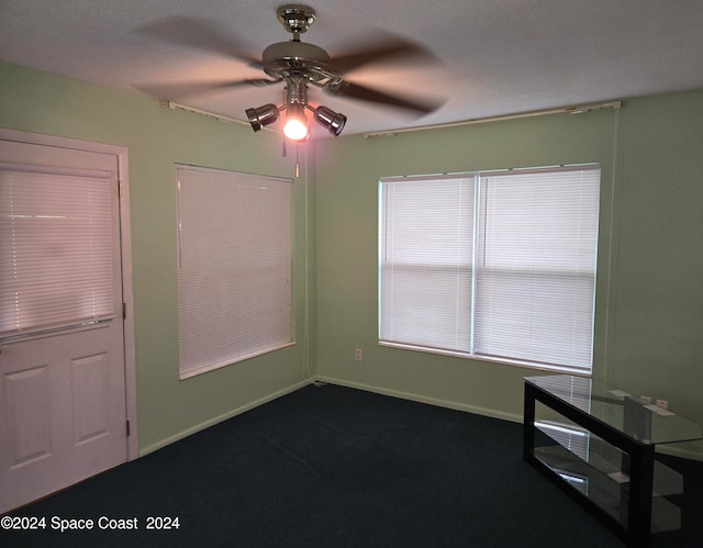 unfurnished bedroom with dark carpet, ceiling fan, and a closet