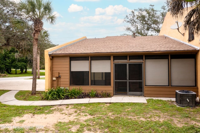 back of house featuring cooling unit, a lawn, and a sunroom