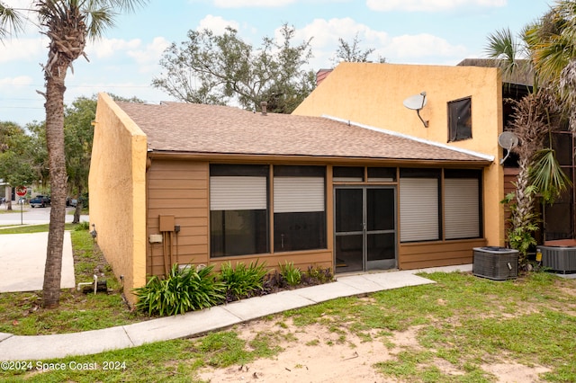 rear view of property with a lawn and central air condition unit