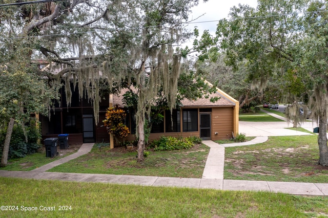 obstructed view of property featuring a front lawn and a sunroom