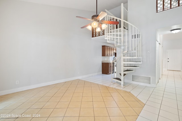 interior space with ceiling fan, a towering ceiling, and tile patterned floors