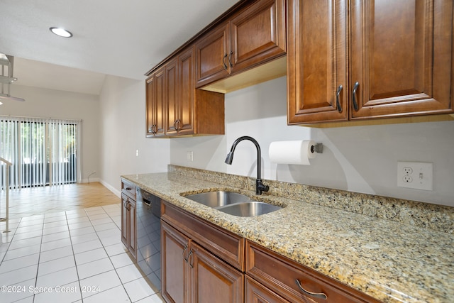kitchen with light tile patterned flooring, light stone counters, a sink, dishwashing machine, and baseboards