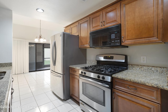 kitchen featuring brown cabinetry, light stone counters, appliances with stainless steel finishes, and an inviting chandelier