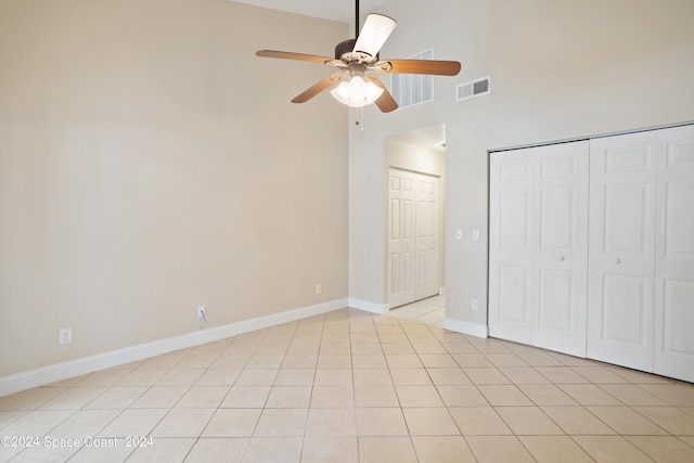 unfurnished bedroom with a high ceiling, ceiling fan, and light tile patterned flooring