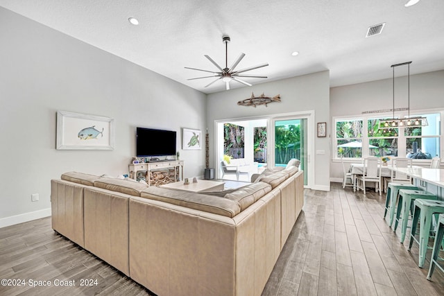 living room featuring light wood-type flooring, a textured ceiling, and a chandelier