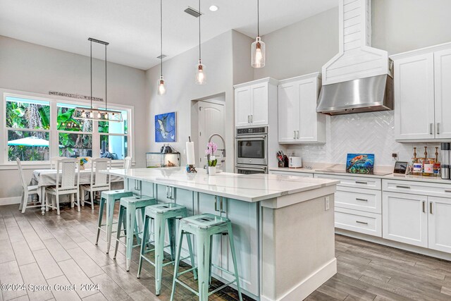 kitchen with white cabinetry, an island with sink, and decorative light fixtures