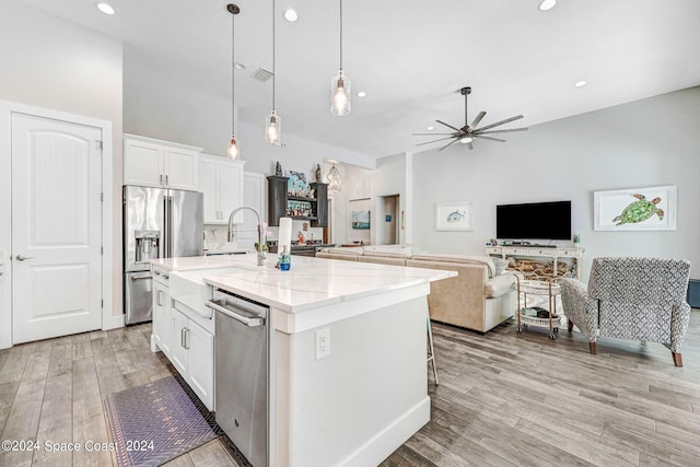 kitchen featuring a kitchen island with sink, white cabinets, stainless steel appliances, decorative light fixtures, and ceiling fan