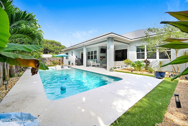 view of swimming pool featuring a sunroom and a patio area