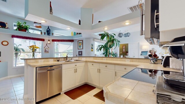 kitchen featuring a high ceiling, sink, kitchen peninsula, and stainless steel dishwasher