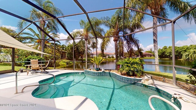 view of pool featuring glass enclosure, a water view, and a patio area