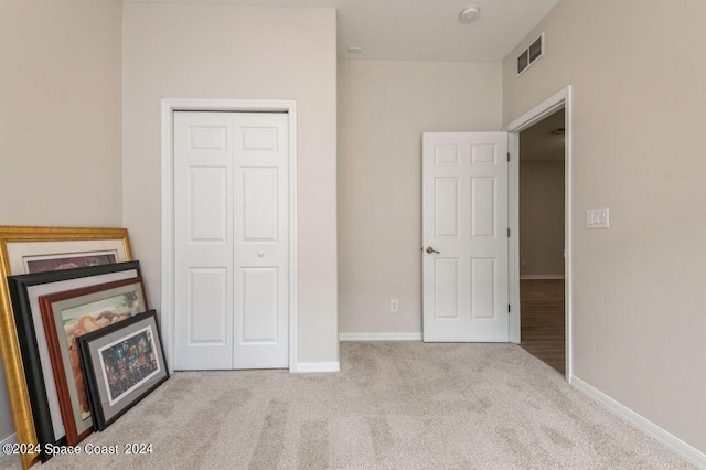 unfurnished bedroom featuring light colored carpet and a closet