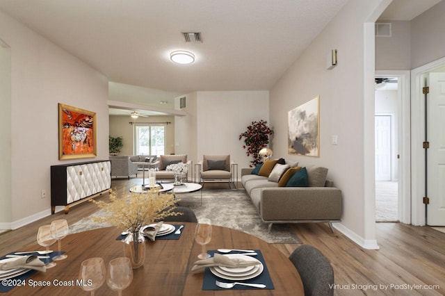 living room featuring ceiling fan, wood-type flooring, and a textured ceiling