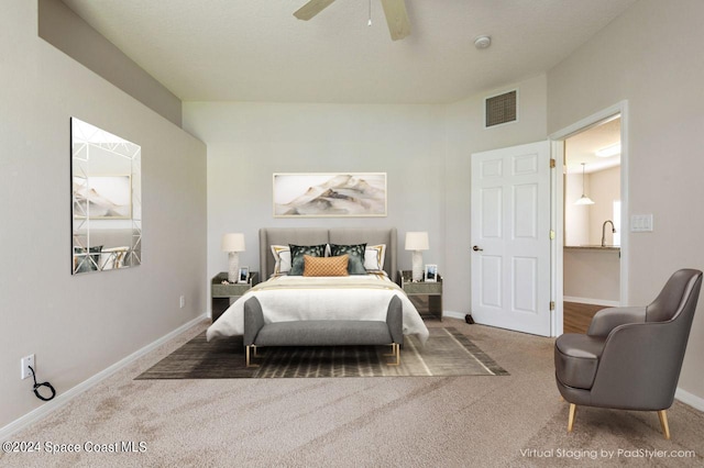 carpeted bedroom with ceiling fan and sink