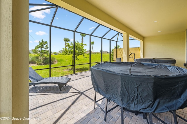 view of patio / terrace featuring a lanai and a hot tub