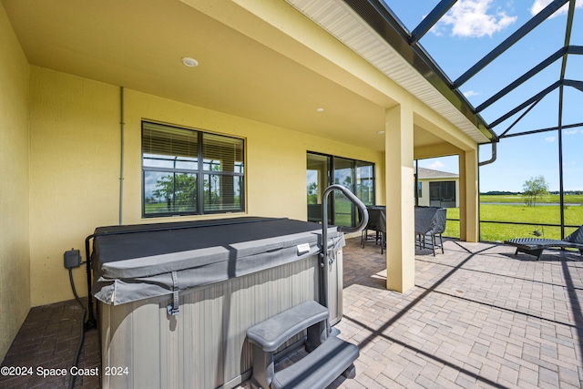 view of patio with glass enclosure and a hot tub