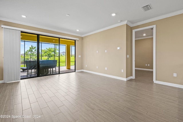 unfurnished room with baseboards, wood finished floors, visible vents, and crown molding