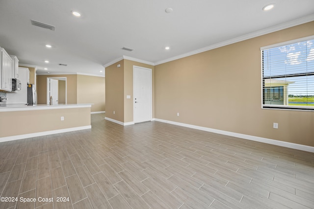 unfurnished living room featuring ornamental molding, sink, and light wood-type flooring