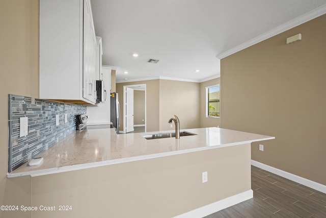 kitchen with visible vents, decorative backsplash, a peninsula, stainless steel appliances, and a sink