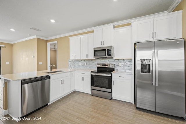 kitchen featuring stainless steel appliances, light countertops, decorative backsplash, a sink, and a peninsula