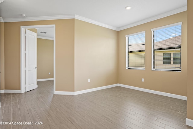 empty room with baseboards, light wood-type flooring, visible vents, and crown molding