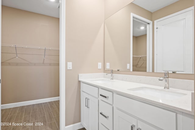 full bathroom with wood tiled floor, a sink, baseboards, and double vanity