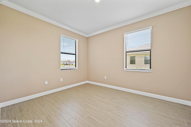 unfurnished room featuring baseboards, light wood finished floors, and crown molding