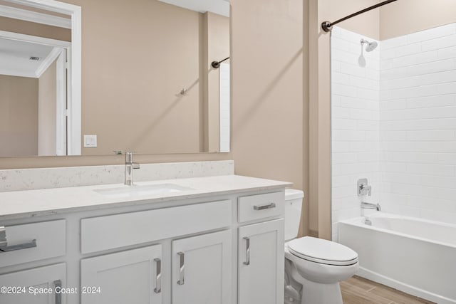 full bathroom featuring toilet, hardwood / wood-style floors, tiled shower / bath, vanity, and crown molding