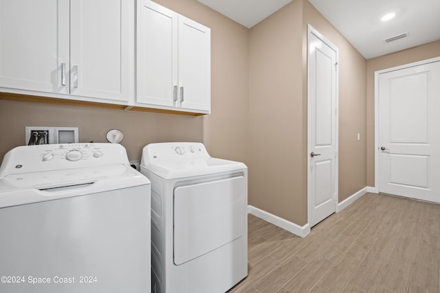 laundry room featuring light hardwood / wood-style flooring, cabinets, and independent washer and dryer