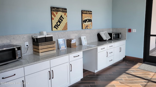 kitchen with white cabinets, light stone countertops, decorative backsplash, and dark hardwood / wood-style flooring